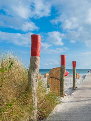 Ein Holzsteg führt zum Meer an einem Strand mit Strandkörben